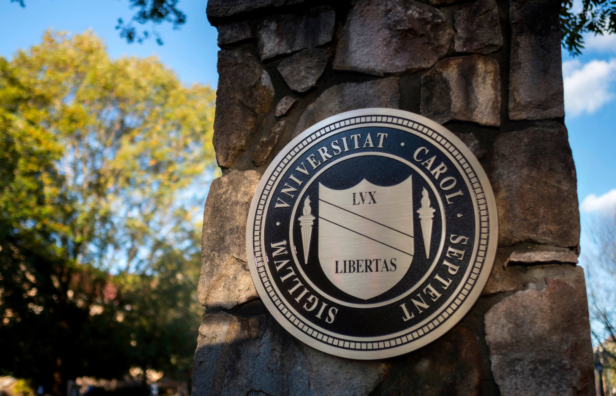 The seal of the University on a stone column by an entrance to UNC's campus.
