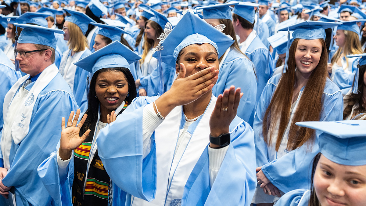 A graduate blowing a kiss with her hand at Winter Commencement.